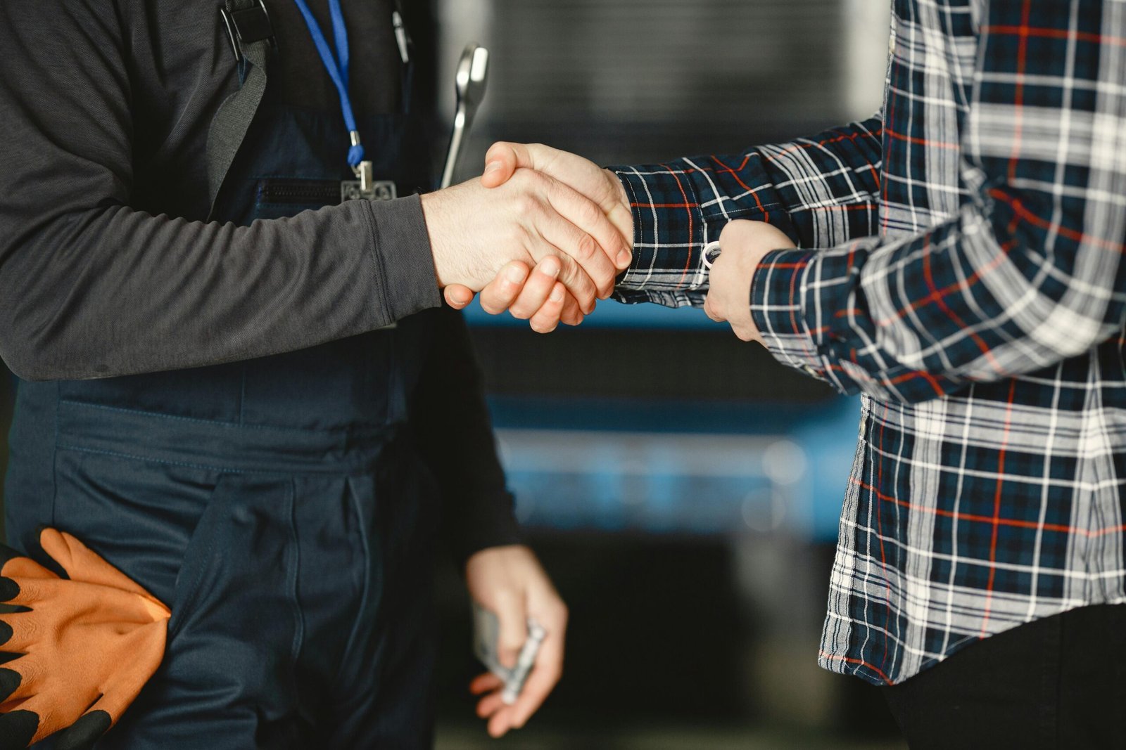 Close-up of a handshake between workers in a workshop, symbolizing business agreement and teamwork.